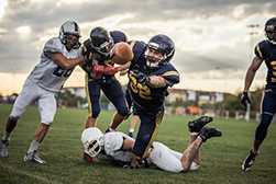 Football players diving and tackling one another causing a potential injury.