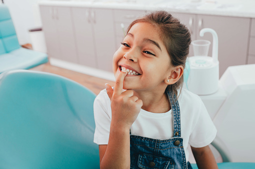 Little girl pointing at her teeth after her pediatric tooth extraction done at Surprise Oral & Implant Surgery in Surprise, AZ