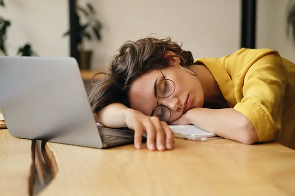 Tired woman sleeping on her laptop before treatment at Surprise Oral & Implant Surgery in Surprise, AZ