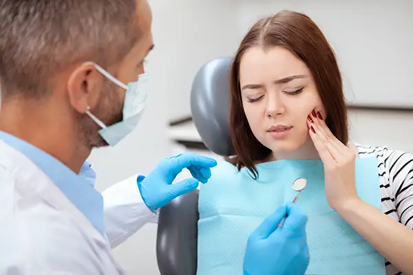 Female patient in a dental chair, holding her jaw and describing her pain from dry socket to an oral surgeon at Surprise Oral & Implant Surgery in Surprise, AZ