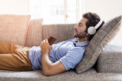 A man relaxing on the couch wearing headphones